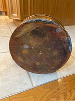 Underside of copper kettle showing tarnish, rust and repairs