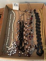 Box with assorted necklaces of pearls, chains, beads, cabochon link