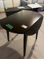 Table with one leaf raised showing leg structure and dark wood finish