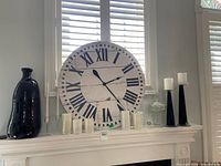 Overall lot on mantel showing wall clock, black glass vase, candlestick holders, crystal dish, candles