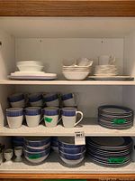 Cabinet shelves showing blue diamond pattern mugs, bowls, plates and additional plain white pieces