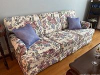Front view of floral sofa with two blue pillows
