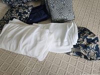 Stacked textiles showing floral curtain fabric, white sheer panel and additional patterned fabric