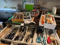 Overall view of countertop and open drawer showing flatware tray, knife block, rolling pin box, utensils and tools