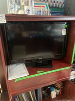 Front view of LG TV on stand inside unit, manual visible