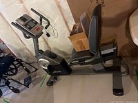 Full side view showing bike frame, seat, console, cardboard box and accessories