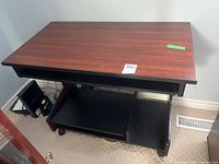 Front angled view of desk showing top surface, keyboard tray slot, lower shelf, casters
