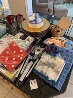Overview of lot showing chargers, plates, glasses, napkins, grilling tools, napkin rings, linens
