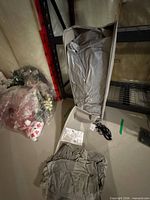 Open grey carry bag showing folded air mattress, separate fabric pieces, power cord, instruction sheet