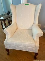 Full view of cream jacquard wingback chair on wooden cabriole legs