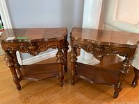 Front view of both demi-lune tables showing carved details, legs and shelves