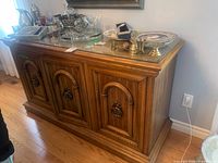 Full view of wood sideboard with glass top and items on surface