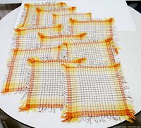 All ten matching woven plaid mats laid out to show quantity and overall pattern