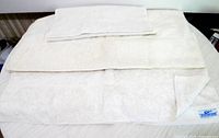 Three cream towels stacked showing sizes and front corner tag