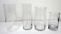 All four clear cylindrical glass vases side‐by‐side showing relative heights and condition