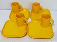 Overhead view of four yellow tray and mug sets