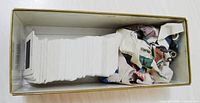 Cardboard box holding a long stack of white 35mm mounted slides with crumpled newspaper filler