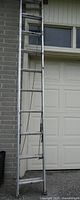 Full ladder leaning against house showing overall length and sections