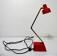 Side view of red Tensor Model 1500 desk lamp showing adjustable arm, shade, base and attached power cord