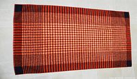Full view of red-orange and black grid-pattern bath mat