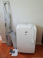 Front view of LG portable AC with hose, window panel, remote and manual