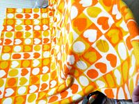 Full view of orange, yellow, white hearts pattern blanket spread out