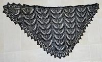 Full view of triangular black lace shawl laid flat