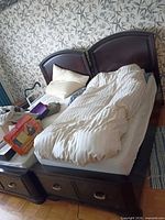 Full view of bed with mattress, pillows, bedding and boxed heating pad on top