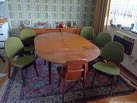 Dining table with six green-upholstered chairs on rug