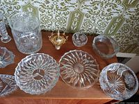 Group of cut crystal pieces including plates, jar, bowls, brass votive