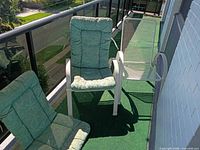 Two metal mesh chairs with green cushions on balcony
