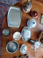 Group view of metal serveware, kettle, stoneware pot and stainless pieces