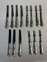 Full set of fruit knives and forks grouped in rows