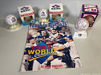 Overview showing all items: book, three replica baseballs on stands, two cardboard sleeves
