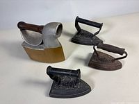 Group of four antique irons on table