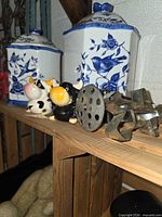 Overview of blue and white canisters, cow shakers, masher and cookie cutters on shelf