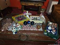 Overview of all decorations on table: topper, wooden ornaments, bags of glass ornaments, boxed lights, boxed shatterproof balls