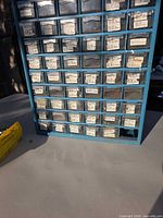 Front view of blue 60-drawer cabinet showing labeled drawers, one drawer missing