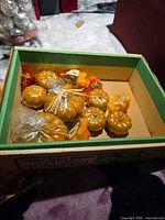 Box containing multiple small artificial pumpkins and gourds