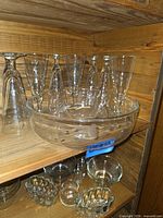 Shelf view of eight inverted pilsner glasses and large etched crystal bowl