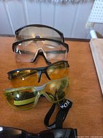 Stacked view of four safety or protective eyewear on tabletop