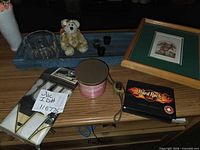 Group shot showing framed watercolor, playing cards, candle, vase, flag, tray, bear, votive holders, pendant