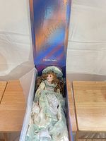 Doll lying in original box with dress and hat visible