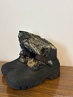 Boots left side view showing camo upper, black rubber lower, tread sole