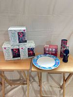 Overall view of three boxed glass sets, plate, tin tube and bottle package on tables