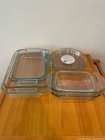 Stacked rectangular baking dishes with teal rims next to nested loaf pans and separate pie plate