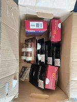 Box containing red Holiday Time 100-count mini light set and several black Magic Tea Lights packs plus tealight blister packs
