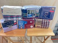 All six sealed queen sheet sets displayed on tables