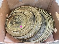 Stack of brass embossed wall plates inside box