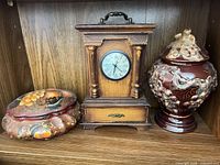 Clock, urn and tin box grouped on shelf